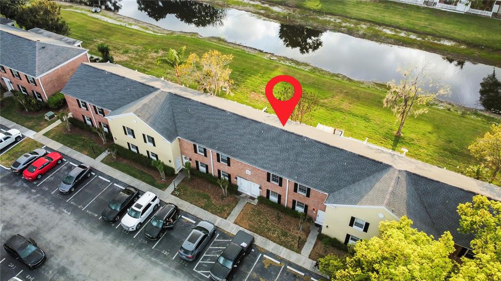 An aerial view shows a multi-unit residential building with a parking lot and a canal — 13706 ORANGE SUNSET DRIVE UNIT 53G, TAMPA, FL