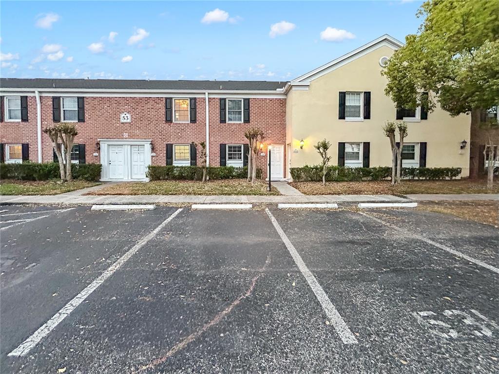 A two-story brick and stucco townhouse building sits behind a paved parking lot — 13706 ORANGE SUNSET DRIVE UNIT 53G, TAMPA, FL
