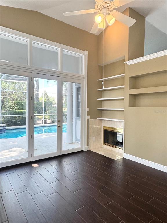 A living room features dark wood-look tile floors, a fireplace, built-in shelving, and pool views — 1250 E LANGLEY COURT, LAKE MARY, FL