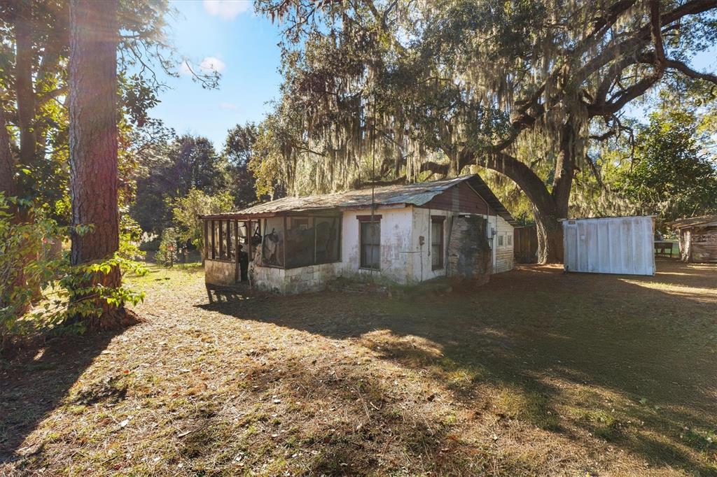 A weathered, single-story house with a screened porch sits under large trees with Spanish moss — 1582 S US 301, SUMTERVILLE, FL