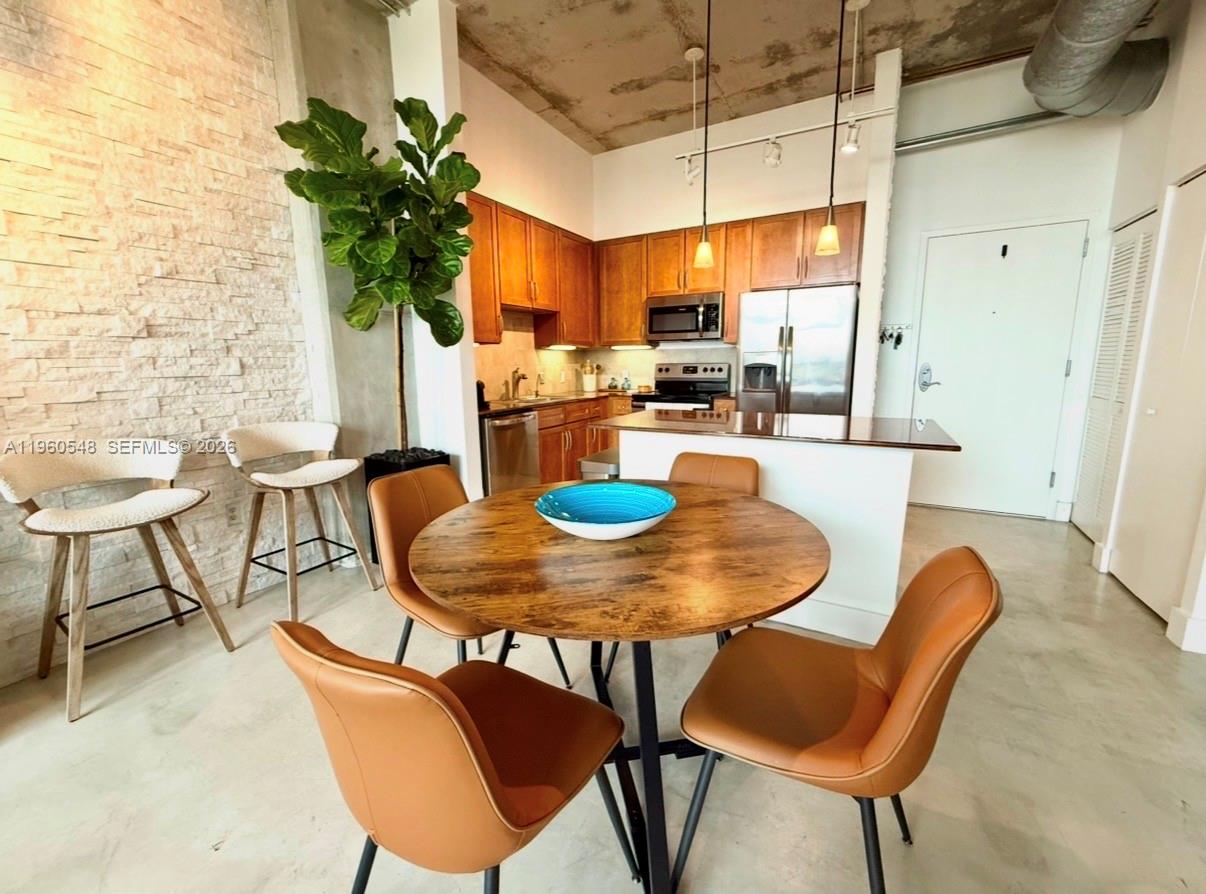A dining area with a round table and chairs sits before an open-concept kitchen — 2001 Biscayne Blvd # 3608, Miami FL 33137, MIAMI, FL