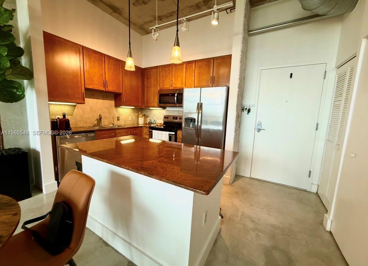 A kitchen features wood cabinets, stainless steel appliances, a granite island, and concrete flooring — 2001 Biscayne Blvd # 3608, Miami FL 33137, MIAMI, FL