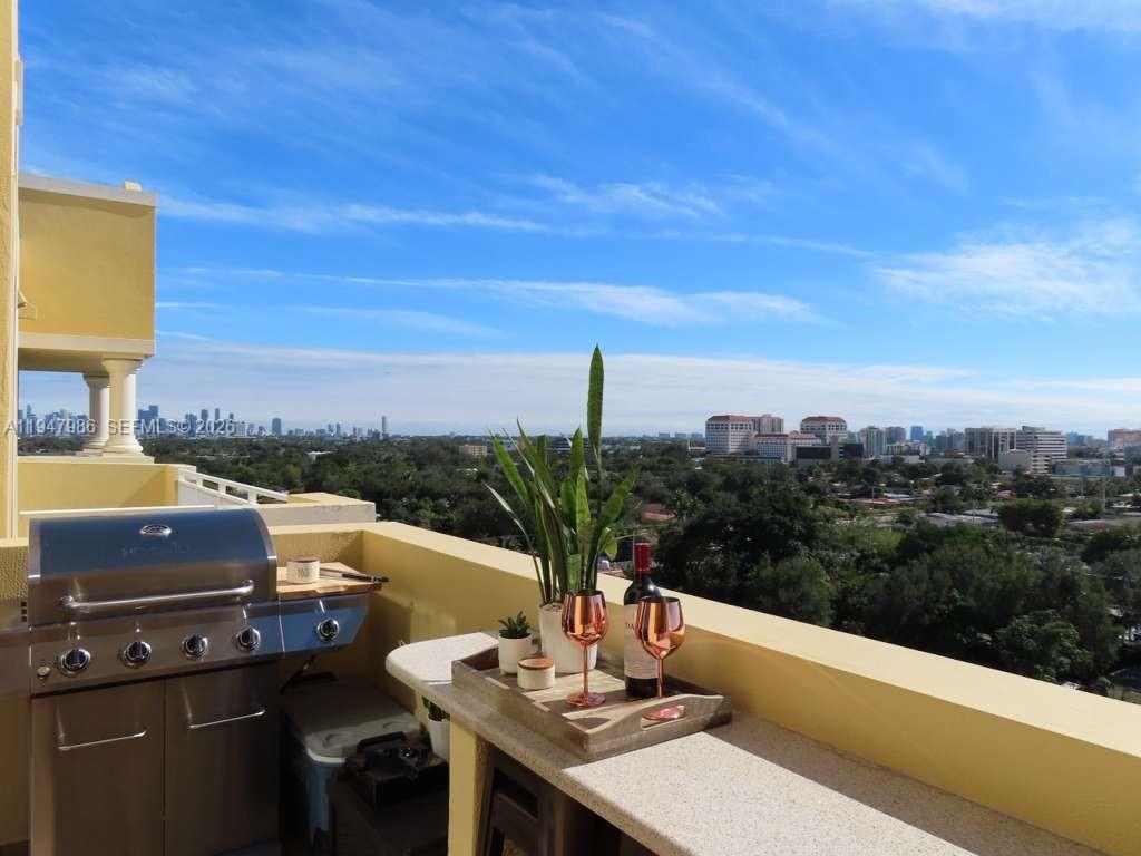 An elevated view of a suburban neighborhood with lush trees and distant city buildings at sunset — 215 SW 42nd Ave, Miami FL 33134, MIAMI, FL