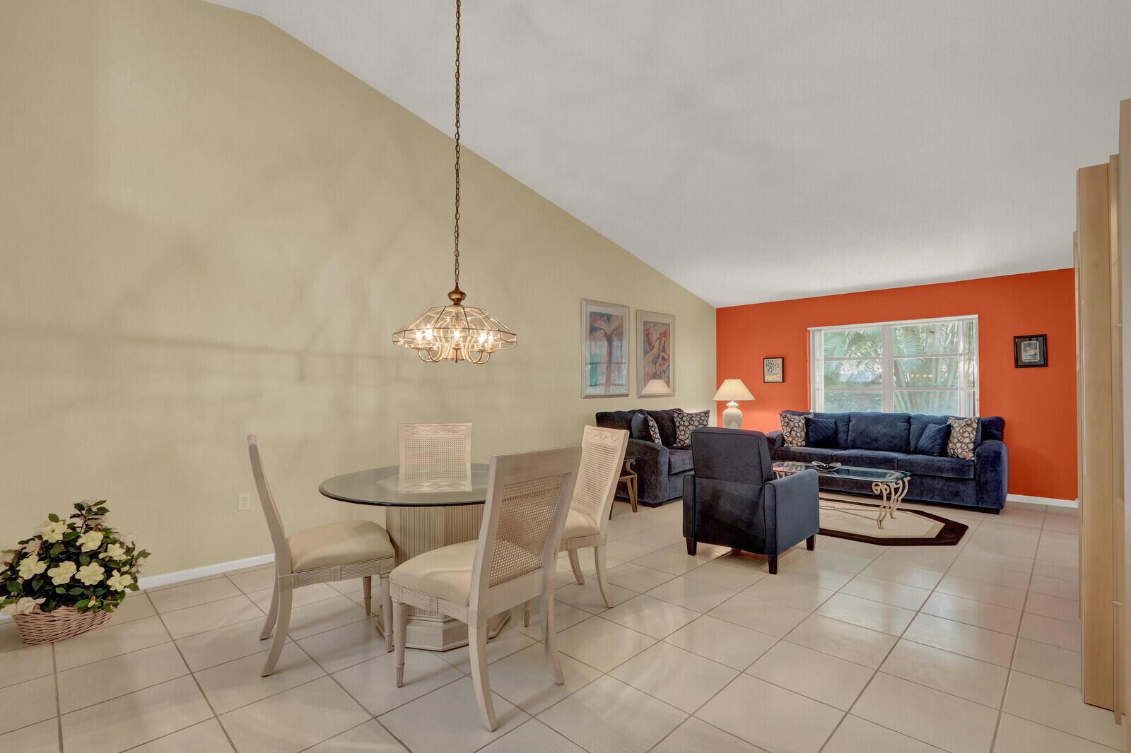 A dining area with a glass table and chairs opens into a living room with orange walls — 9904 Summerbrook Terrace # B, Boynton Beach FL 33437, BOYNTON BEACH, FL
