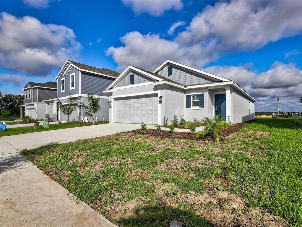 A single-story house with a gray stucco exterior, a two-car garage, and a blue front door — 602 BELL PRAIRIE CIRCLE, LAKE WALES, FL