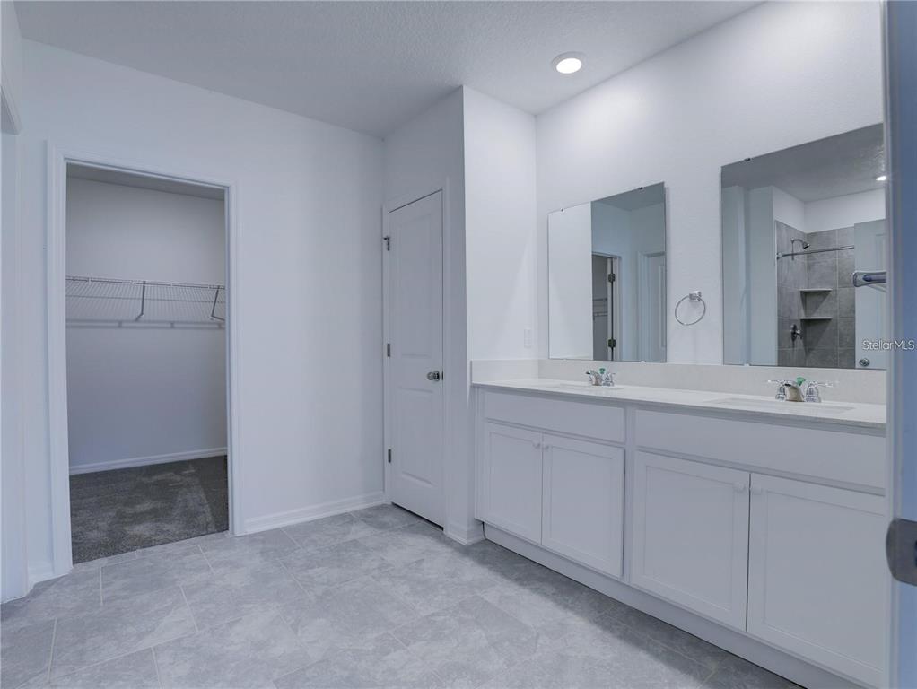 A bathroom features a double vanity with white cabinets, two mirrors, and an adjacent closet — 602 BELL PRAIRIE CIRCLE, LAKE WALES, FL