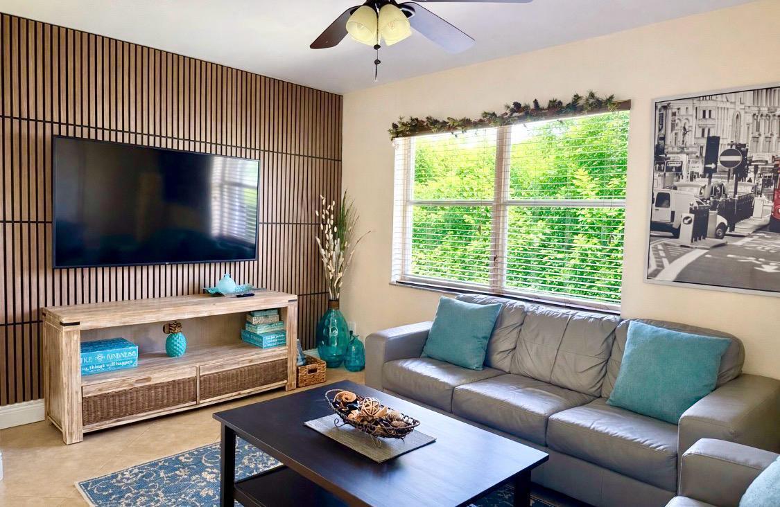 A living room features a wood-slat accent wall, a television, a sofa, and a coffee table — 803 NE 2nd Avenue, Delray Beach FL 33444, DELRAY BEACH, FL