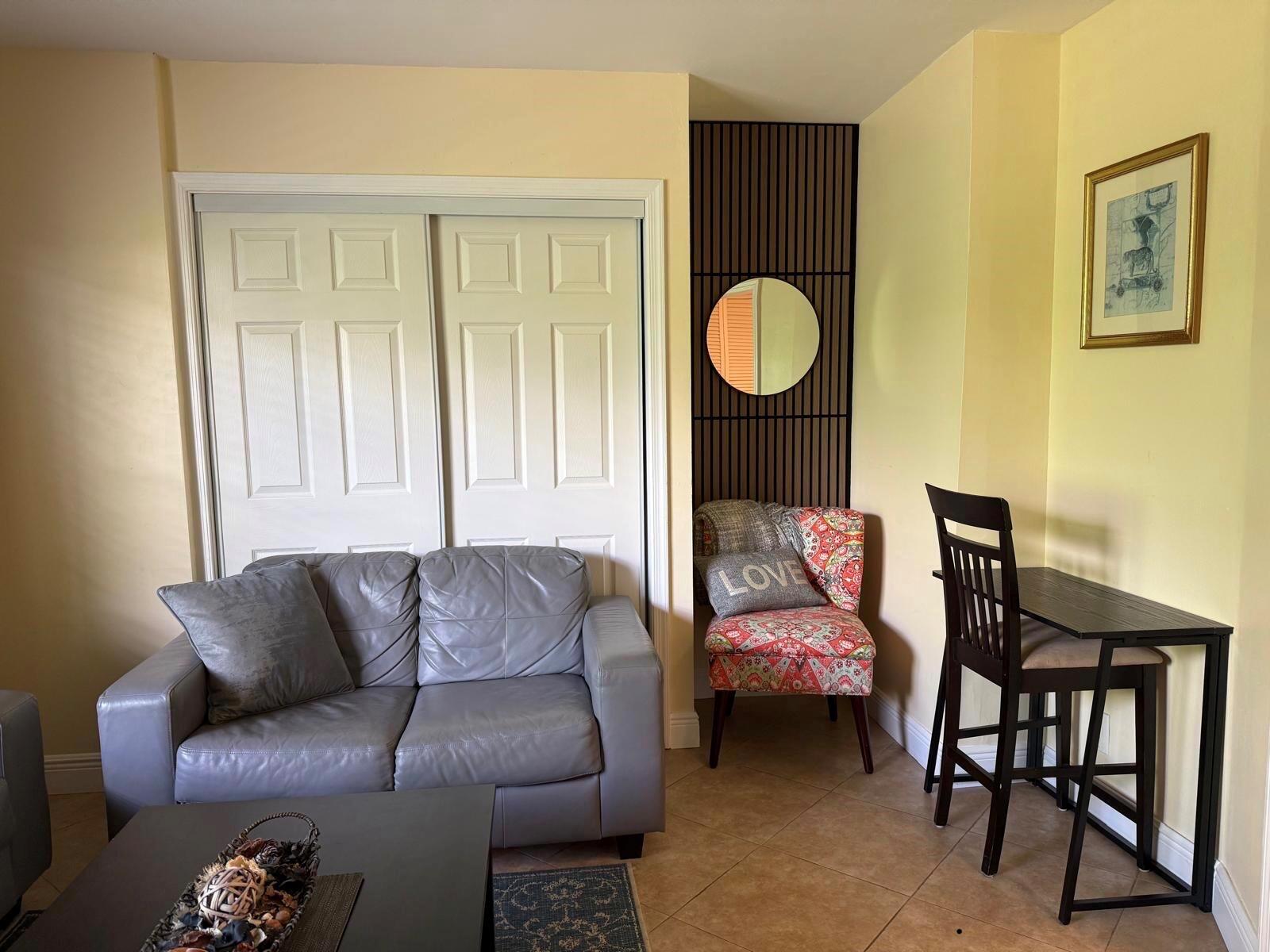 A living room features a gray sofa, a patterned accent chair, and a small dining table — 803 NE 2nd Avenue, Delray Beach FL 33444, DELRAY BEACH, FL