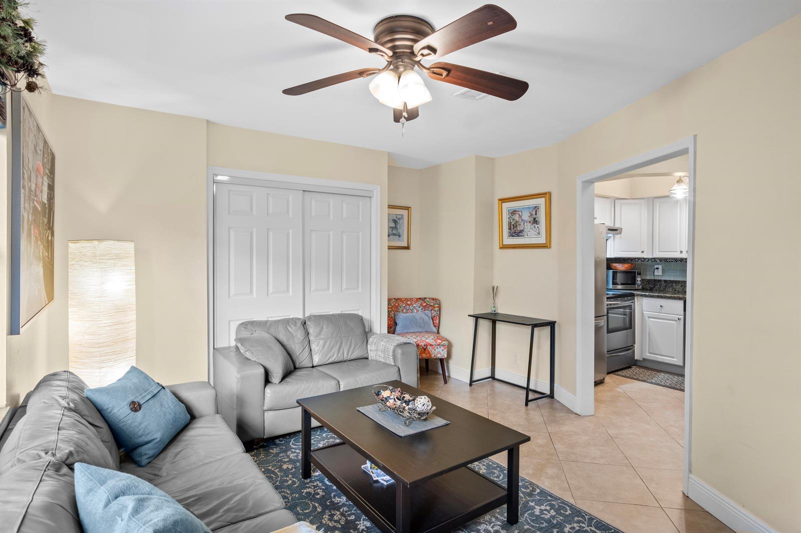 A living room with a ceiling fan, gray leather sofas, and a view into a kitchen — 803 NE 2nd Avenue, Delray Beach FL 33444, DELRAY BEACH, FL