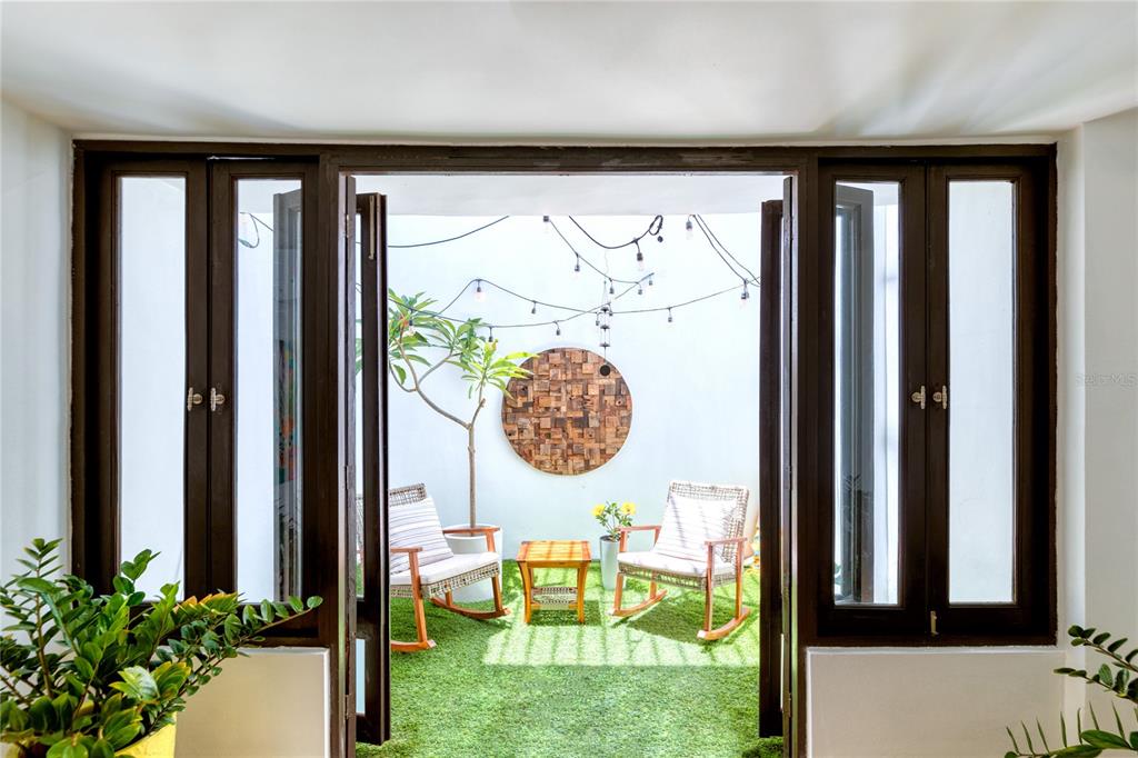 A view through open glass doors reveals a small patio with artificial turf and rocking chairs — 203 FORTALEZA STREET UNIT 4, SAN JUAN, PR
