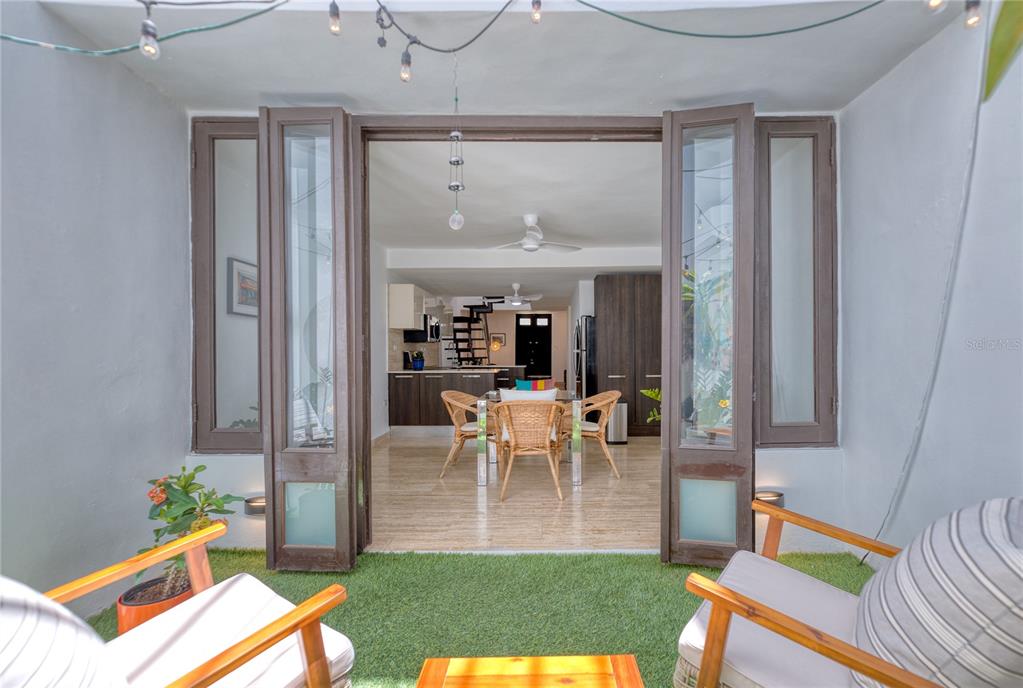 A patio with artificial turf and chairs looks through open glass doors into a kitchen — 203 FORTALEZA STREET UNIT 4, SAN JUAN, PR