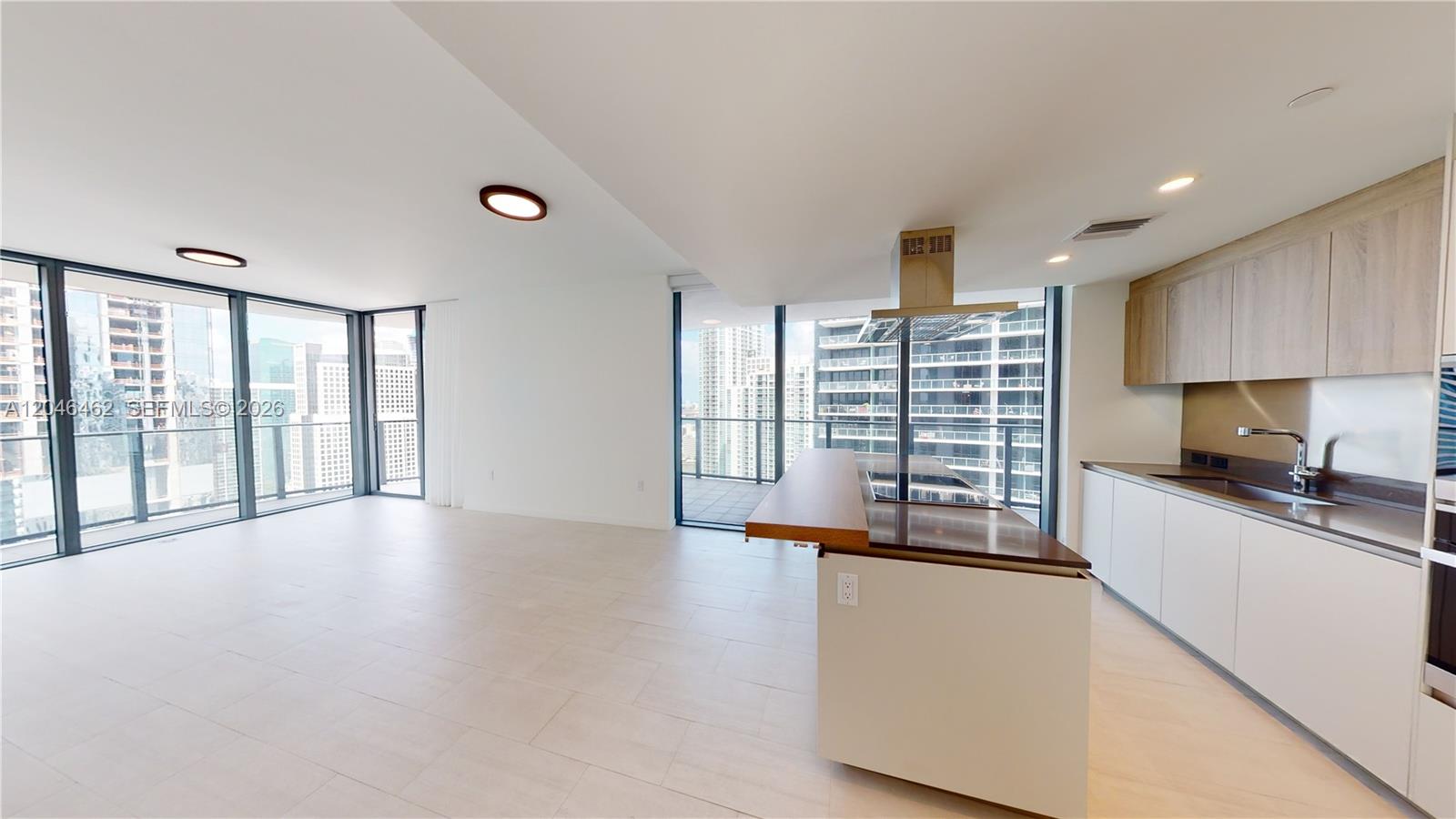 A modern kitchen and living area feature floor-to-ceiling windows, light tile flooring, and city views — 1000 Brickell Plaza # 3915, Miami FL 33131, MIAMI, FL