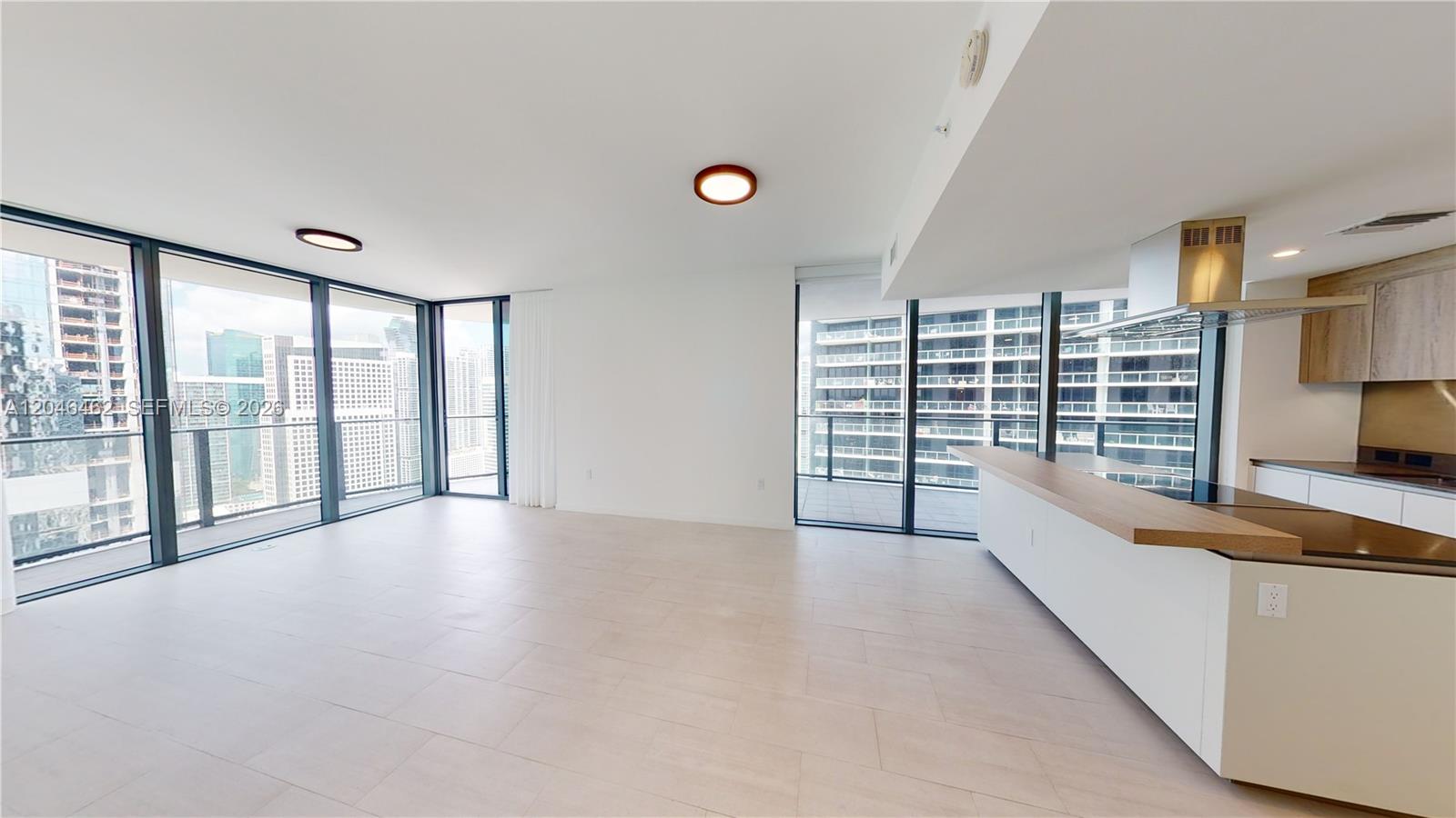 A modern open-plan living area features floor-to-ceiling windows, light tile flooring, and a kitchen island — 1000 Brickell Plaza # 3915, Miami FL 33131, MIAMI, FL