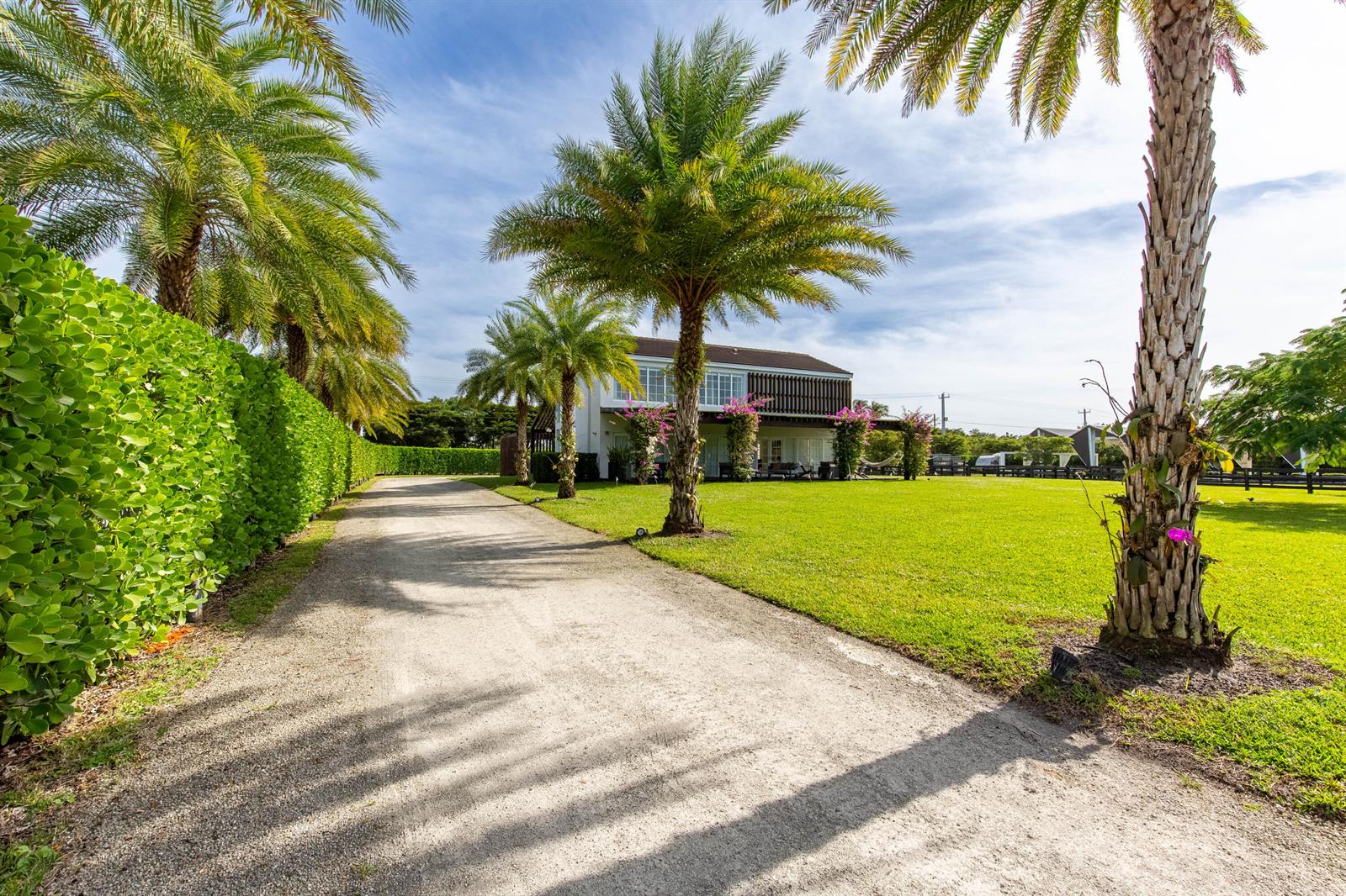 A gravel driveway leads to a two-story house surrounded by palm trees and green lawns — 14432 Rolling Rock  (house) Place, Wellington FL 33414, WELLINGTON, FL