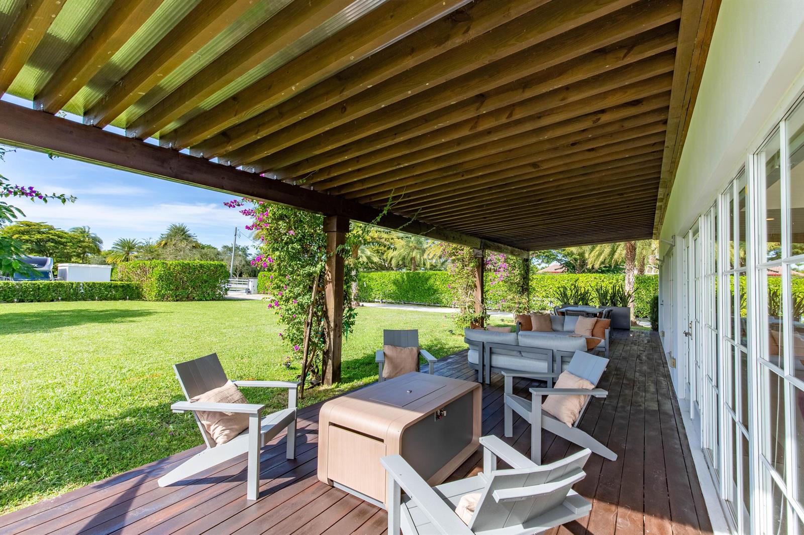 A wooden deck features a pergola, outdoor seating, and a fire pit overlooking a lawn — 14432 Rolling Rock  (house) Place, Wellington FL 33414, WELLINGTON, FL