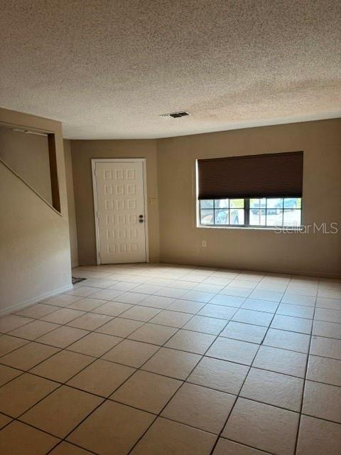 An interior view of a room with beige tile flooring, tan walls, and a white door — 8559 PILGRIM COURT, NEW PORT RICHEY, FL