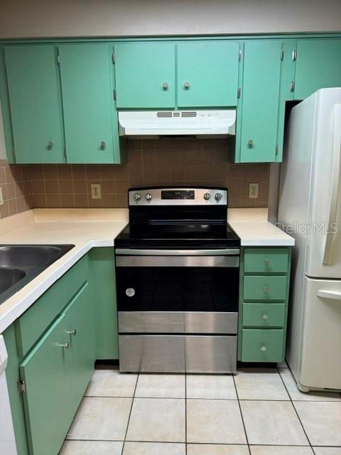 A kitchen features mint green cabinets, a stainless steel stove, and white tile flooring — 8559 PILGRIM COURT, NEW PORT RICHEY, FL