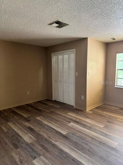An empty room features wood-look flooring, a white louvered closet door, and a window — 8559 PILGRIM COURT, NEW PORT RICHEY, FL