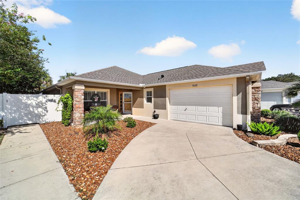 A single-story house with a white garage, stone accents, and a concrete driveway — 628 BERMUDEZ COURT, THE VILLAGES, FL