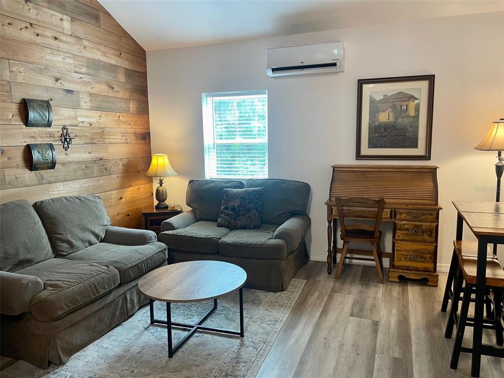 A living room features a wood-paneled accent wall, two sofas, a desk, and a window — 1484 CLEVELAND STREET, CLEARWATER, FL