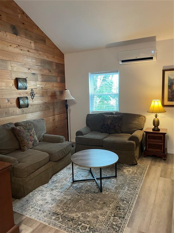 A living room features two sofas, a coffee table, and a wood-paneled accent wall — 1484 CLEVELAND STREET, CLEARWATER, FL