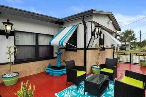 A red wooden deck features a small fountain, outdoor furniture, and striped window awnings — 4143 SE 29th Court, Okeechobee FL 34974, OKEECHOBEE, FL