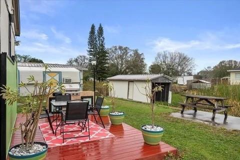 A red wooden deck with patio furniture sits in a backyard featuring a storage shed — 4143 SE 29th Court, Okeechobee FL 34974, OKEECHOBEE, FL