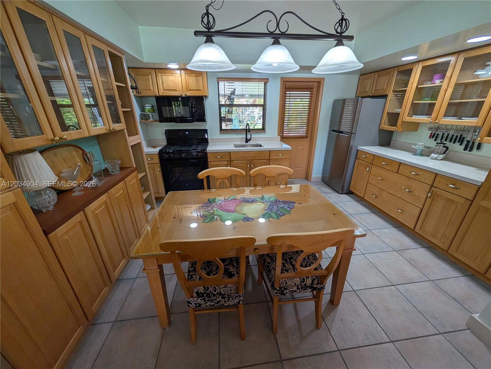 A kitchen features light wood cabinets, a glass-topped dining table, and tile flooring — 29-33 SE 4th, Dania Beach FL 33004, DANIA BEACH, FL