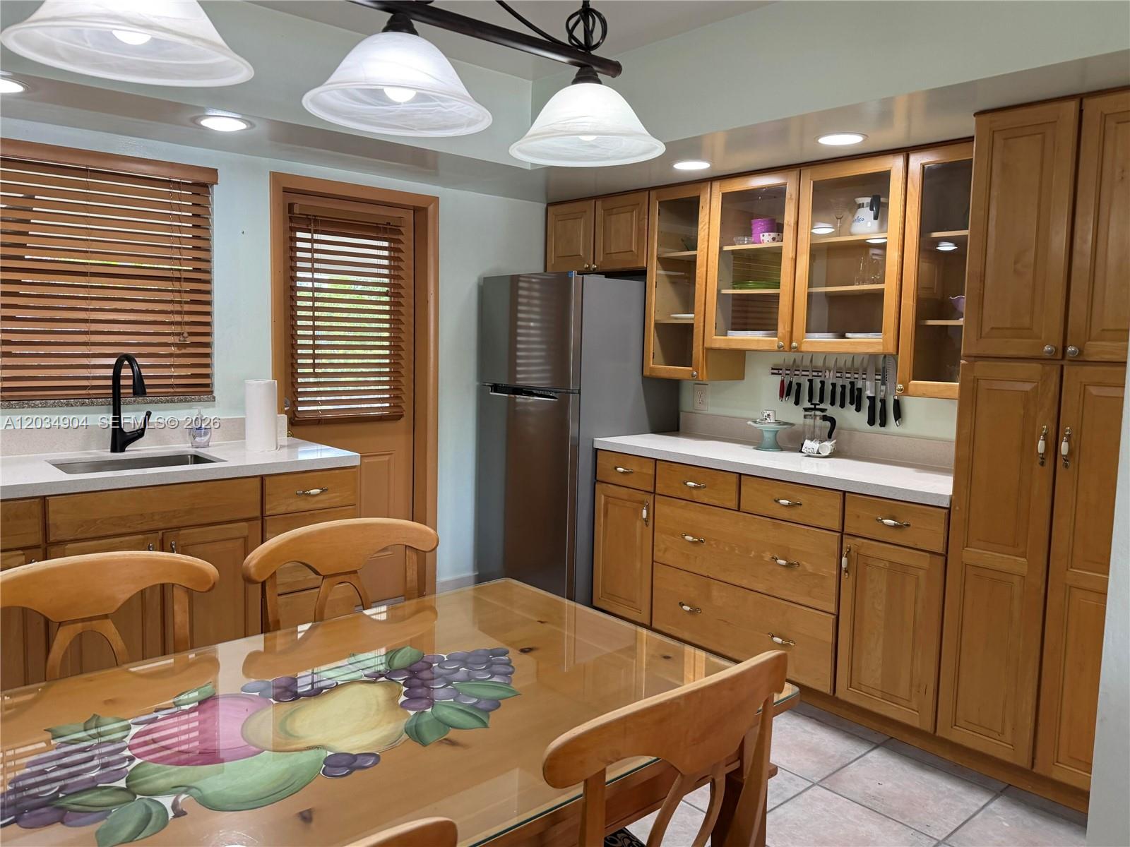 A kitchen features wood cabinets, a stainless steel refrigerator, a dining table, and tile flooring — 29-33 SE 4th, Dania Beach FL 33004, DANIA BEACH, FL
