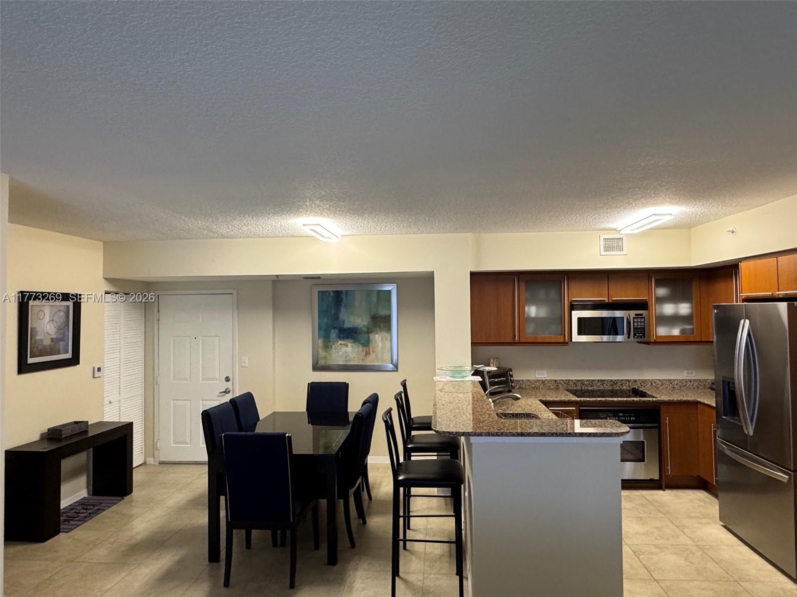 An open-concept kitchen with granite countertops and a dining area with a dark table — 2080 S Ocean Dr # 1405, Hallandale Beach FL 33009, HALLANDALE BEACH, FL