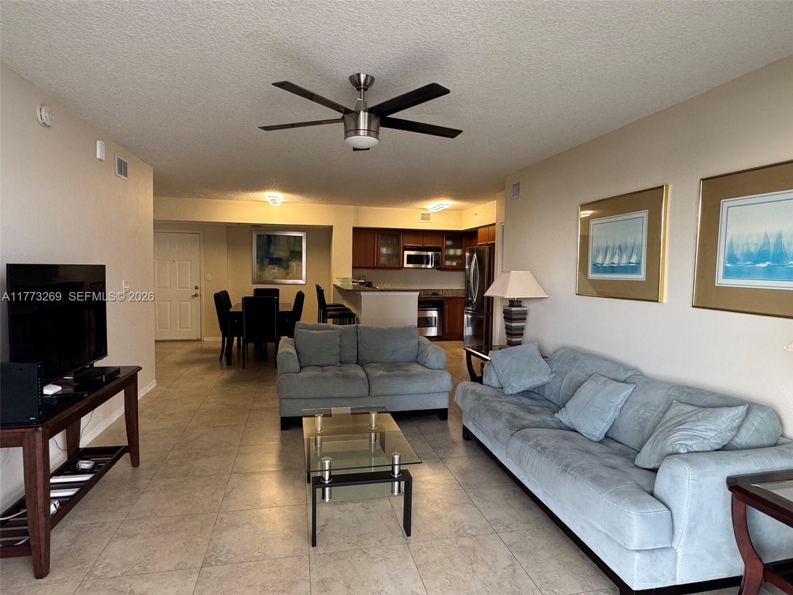 An open-concept living and dining area features tile flooring, a ceiling fan, and kitchen access — 2080 S Ocean Dr # 1405, Hallandale Beach FL 33009, HALLANDALE BEACH, FL