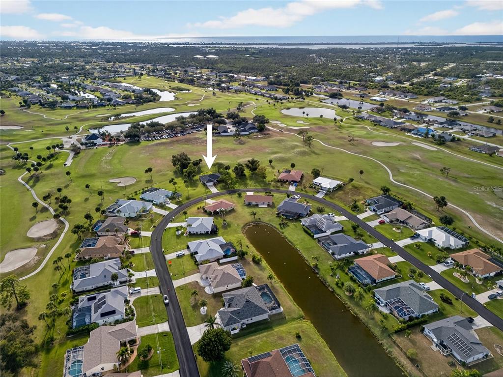An aerial view shows a residential neighborhood with houses surrounding a pond and golf course — 36 BUNKER LANE, ROTONDA WEST, FL