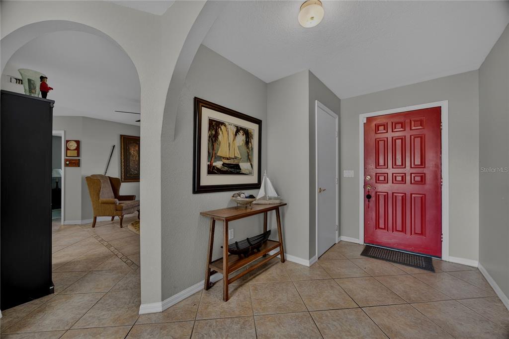 An entryway features a red front door, tiled floors, and an arched opening to a room — 36 BUNKER LANE, ROTONDA WEST, FL
