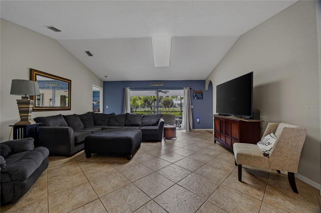 A living room features a large sectional sofa, a television on a console, and tile flooring — 36 BUNKER LANE, ROTONDA WEST, FL
