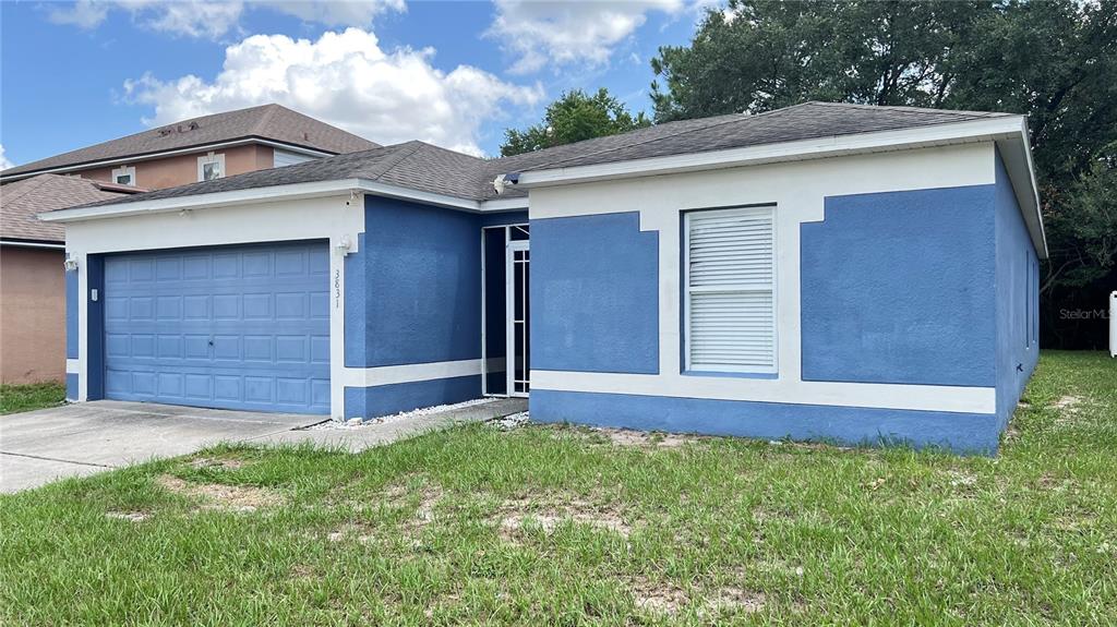 A blue, single-story house with a two-car garage and a white-trimmed window — 3831 CINNAMON FERN LOOP, CLERMONT, FL