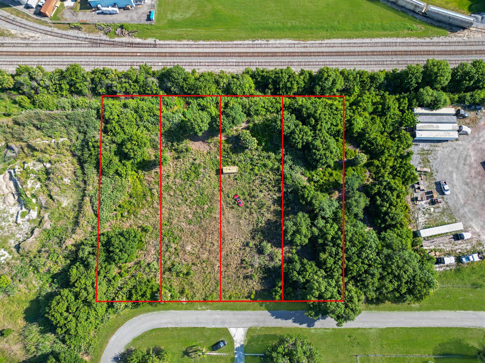 An aerial view shows four adjacent rectangular lots of land bordered by trees and tracks — . NW 7th Court, Okeechobee FL 34972, OKEECHOBEE, FL