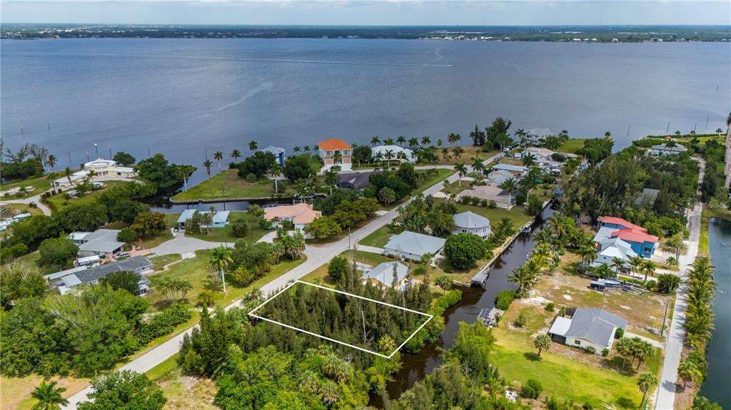 An aerial view shows a vacant, tree-covered lot outlined in white next to a canal — 430 KLISPIE DRIVE, PUNTA GORDA, FL