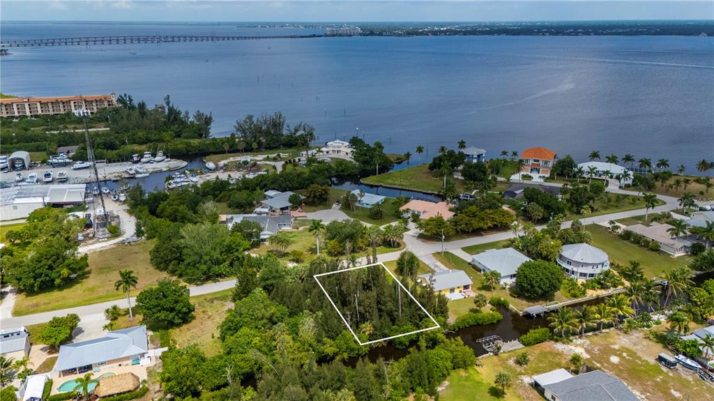 An aerial view shows a wooded residential lot outlined in white near a waterfront area — 430 KLISPIE DRIVE, PUNTA GORDA, FL