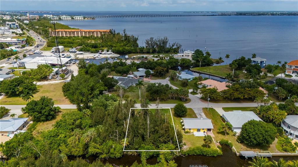 An aerial view shows a vacant, tree-covered lot outlined in white near a waterfront — 430 KLISPIE DRIVE, PUNTA GORDA, FL