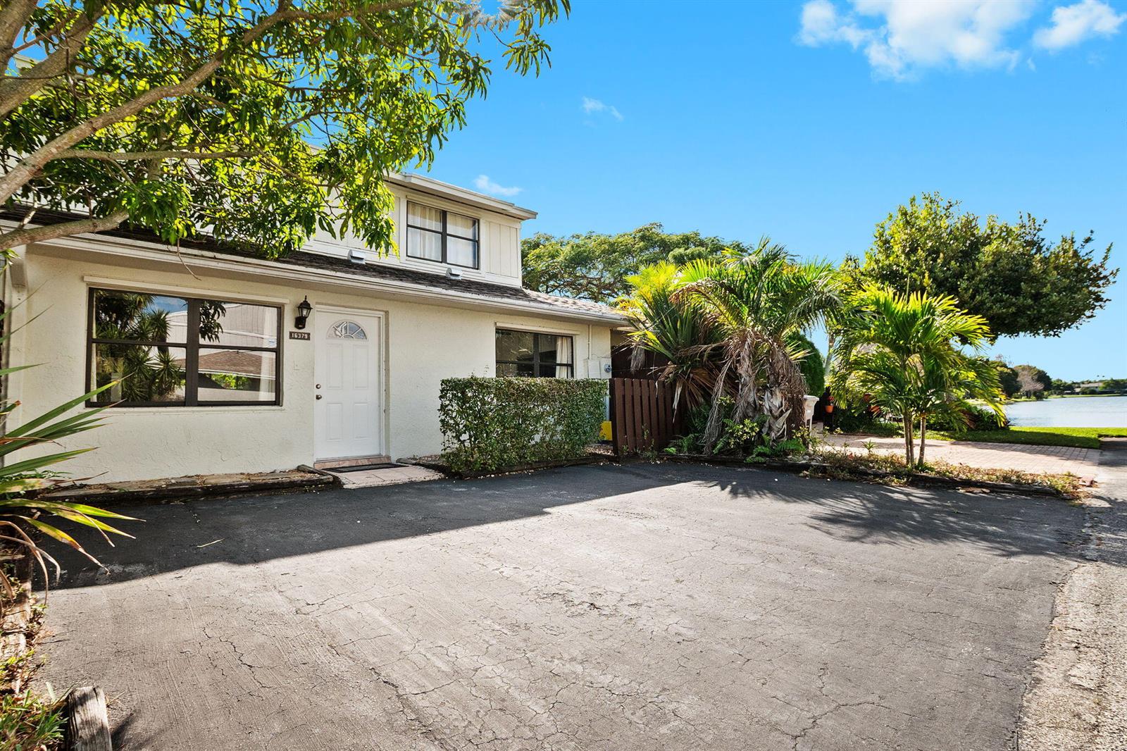 A two-story house with a white exterior, a paved driveway, and palm trees near water — 16379 Water Way, Delray Beach FL 33484, DELRAY BEACH, FL