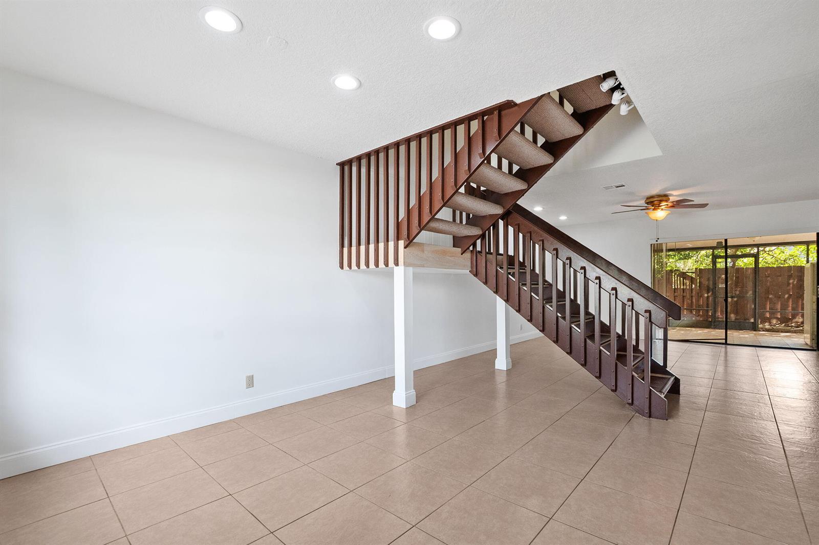 An interior room features light tile flooring, white walls, and a wooden staircase with railings — 16379 Water Way, Delray Beach FL 33484, DELRAY BEACH, FL