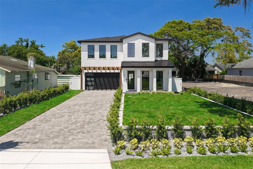A modern two-story white house features a paved driveway, a pergola, and landscaped front yard — 1523 MILLER AVENUE, WINTER PARK, FL