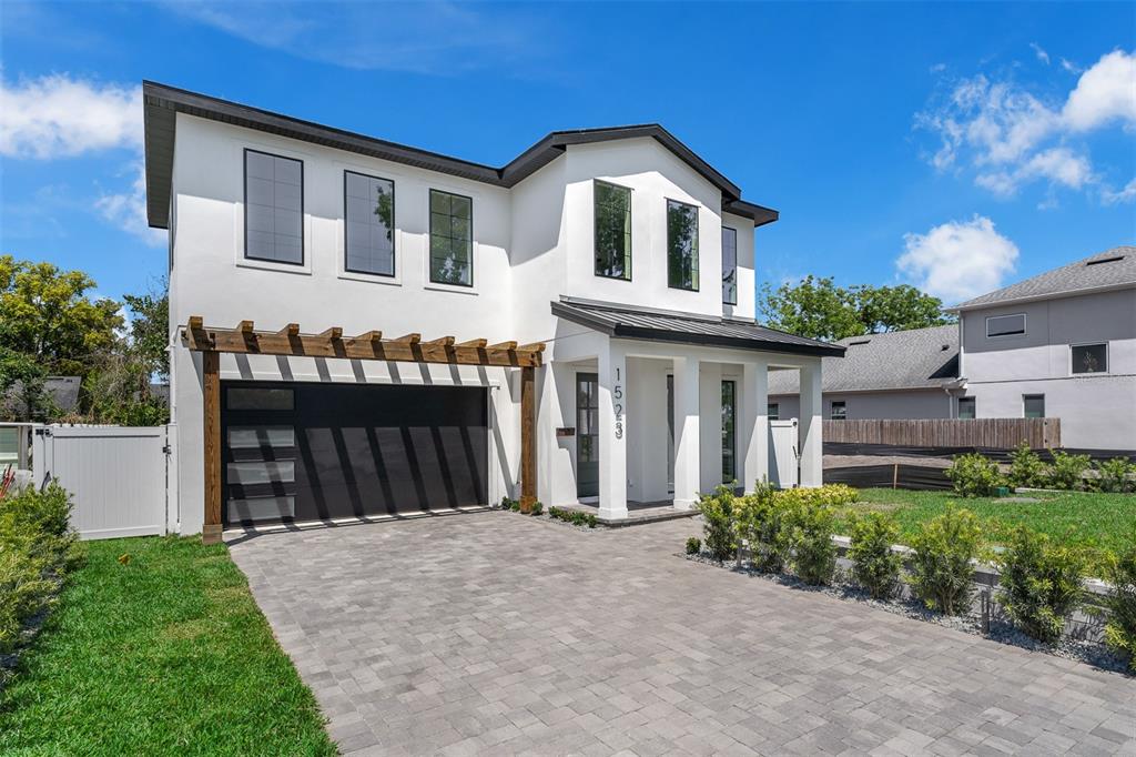 A two-story white house with a black garage door, wooden pergola, and paved driveway — 1523 MILLER AVENUE, WINTER PARK, FL