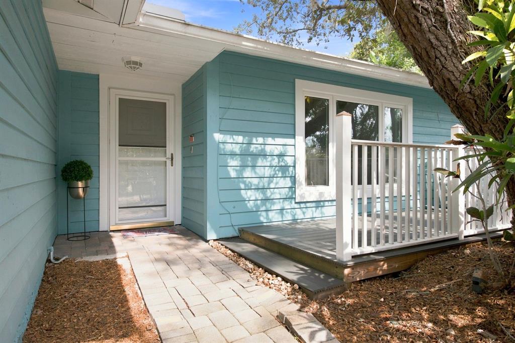 A light blue house exterior features a white front door, a deck, and a walkway — 1111 CARLTON ROAD, TARPON SPRINGS, FL