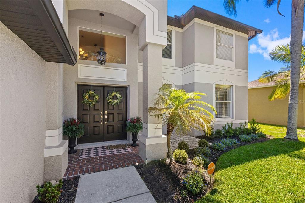A two-story house exterior features a brick entryway, double front doors, and a palm tree — 16127 LYTHAM DRIVE, ODESSA, FL