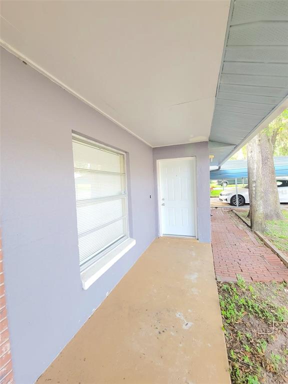 A covered concrete porch leads to a white front door beside a large window — 5338 ORANGE AVENUE UNIT B, SEFFNER, FL