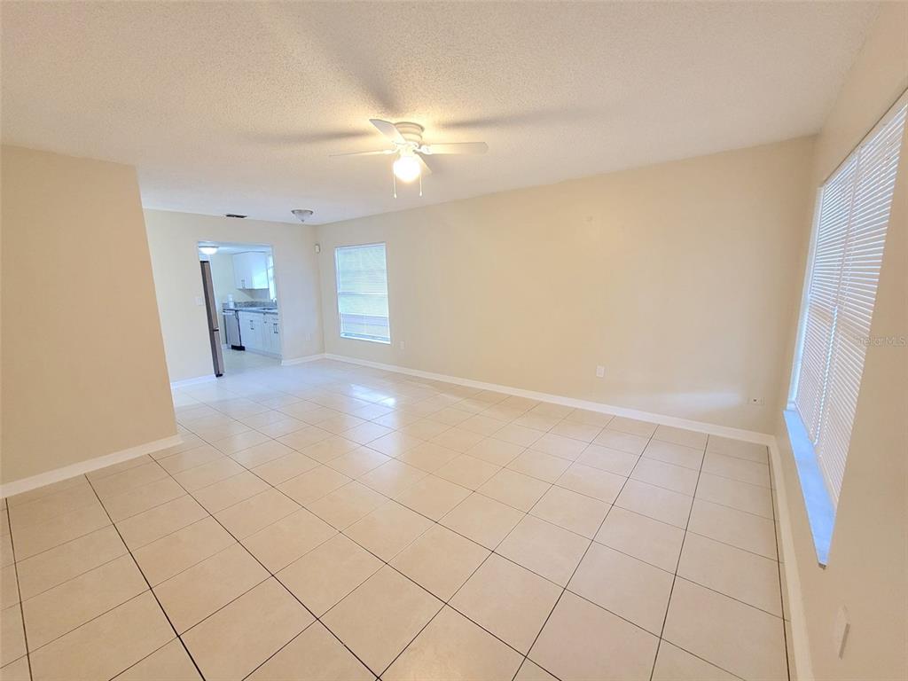 An empty room with beige walls, light-colored tile flooring, and a ceiling fan — 5338 ORANGE AVENUE UNIT B, SEFFNER, FL