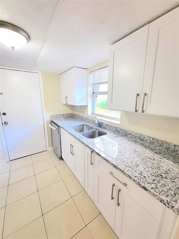 A kitchen features white shaker cabinets, granite countertops, a stainless steel sink, and tile flooring — 5338 ORANGE AVENUE UNIT B, SEFFNER, FL