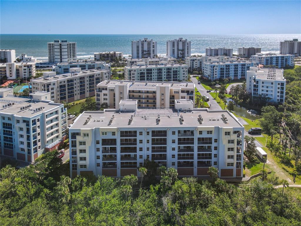 An aerial view of a multi-story apartment complex near the ocean — 5300 S ATLANTIC AVENUE UNIT 10-205, NEW SMYRNA BEACH, FL
