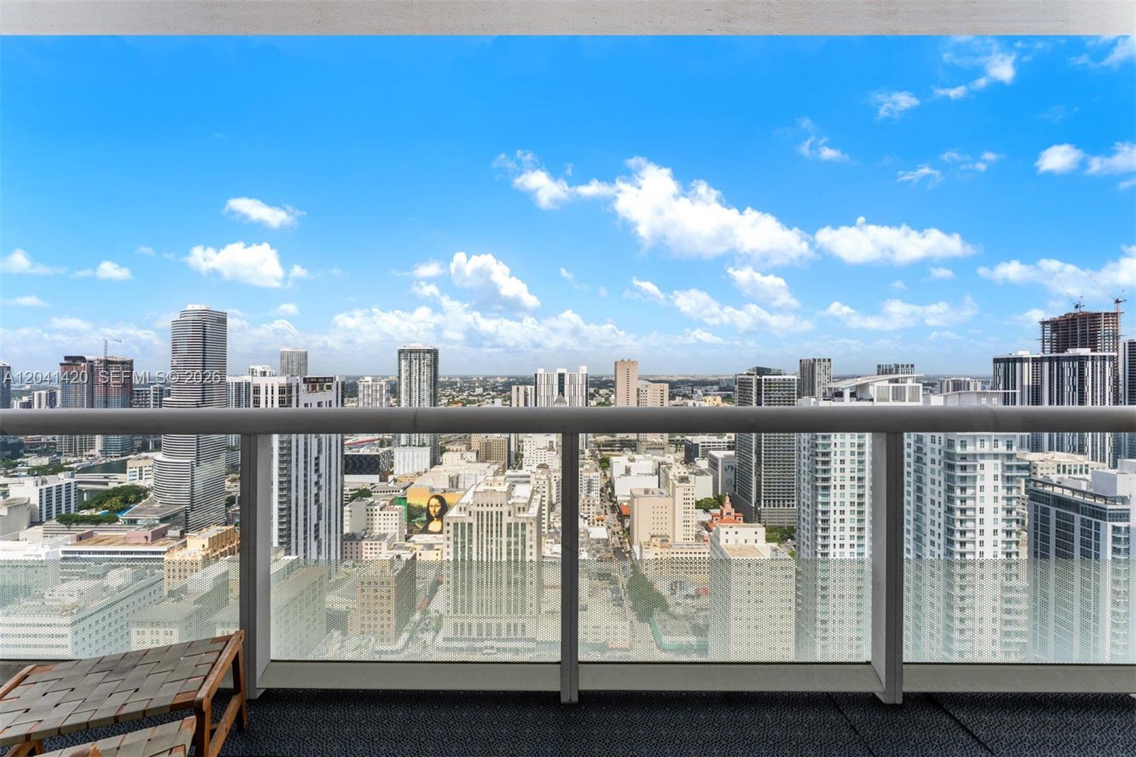 A balcony with a glass railing overlooks a dense city skyline under a blue sky — 50 Biscayne Blvd # 4603, Miami FL 33132, MIAMI, FL